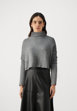 Grijze trui met een hoge nek en textuur in horizontale strepen. Heeft lange mouwen en een cropped ontwerp. Gecombineerd met een zwarte rok.