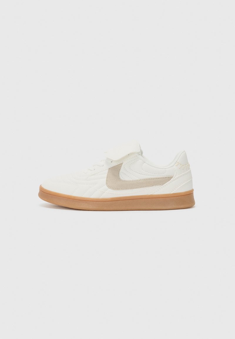Baskets blanches de sport avec un dessus texturé, accent en suède beige et semelle en caoutchouc beige. Présente un design à lacets et un col rembourré.