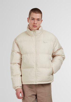Beige Pufferjacke mit gestepptem Design, hohem Kragen und Reißverschluss vorne. Sie verfügt über ein dezentes Muster, elastische Bündchen und eine lockere Passform.