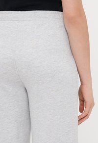 Ανοιχτό γκρι φόρμες με μαλακή υφή, με ελαστική μέση και εφαρμοστή σχεδίαση. Η πίσω όψη δείχνει αδιάκοπη ραφή και κομψή γραμμή.