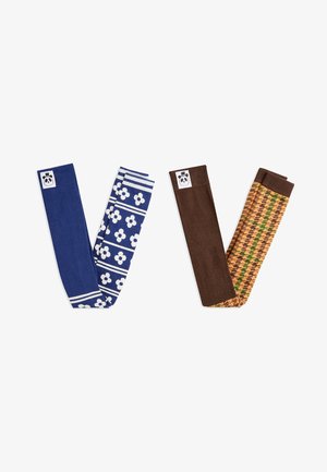 Modré a bílé legíny s květinovým vzorem a hnědé texturované legíny se zelenými akcenty, obě s logy pandy.