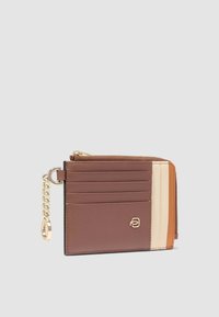 Portafoglio compatto realizzato in pelle liscia nei colori marrone, crema e arancione. Presenta diversi slot per carte, un compartimento con zip e un accento in catena dorata.