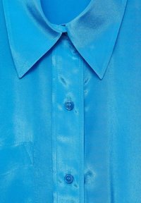 Cyaan blauwe shirt met een glanzende textuur, voorzien van een puntige kraag, een frontale knoopsluiting en een soepele stof met een subtiele glans.