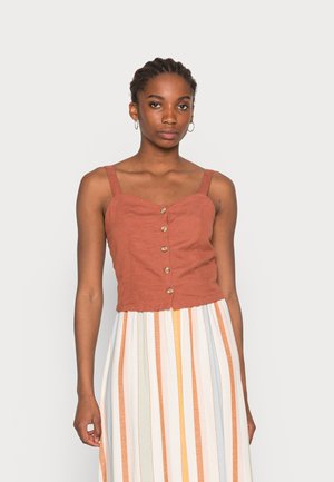 Top cropped de cor ferrugem com decote coração, botões à frente e alças finas; combinado com uma saia de riscas multicoloridas.