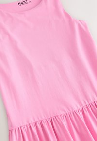 Rosa ärmelloses Kleid mit abgesenkter Taille aus weichem Stoff, mit gerafftem Saum und glatter Textur. Das Etikett zeigt die Marke "NEXT".