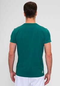 Camiseta de algodón verde con mangas cortas, cuello redondo y detalle de logo cerca del dobladillo. Textura suave; silueta ajustada.