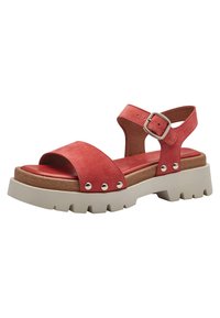 Sandal in suede rosso con una larga fascia frontale, cinturino alla caviglia regolabile, borchie argentate e una robusta suola bianca a piatto.