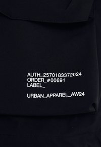 Black fabric featuring white printed text, including order and label details, applied in a clean, legible font. Minimalist design.