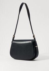 Borsa a spalla in pelle nera con design curvo, tracolla regolabile e hardware in tono dorato. Texture liscia con chiusura a patta singola.