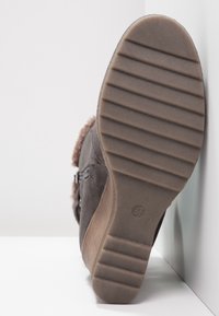 Stivaletto in suede marrone con suola in gomma texturizzata, dotato di una zip laterale e rifinitura in pelliccia sintetica lungo il bordo superiore. Taglia 37.