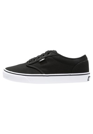 Sneaker nere in tela con suole in gomma bianca, punta arrotondata, cinque fori per i lacci, branding minimale e cuciture in contrasto tra nero e bianco.
