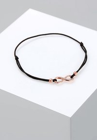 Svart snörearmband med en rose gold oändlighetssymbol som lås och två små rose gold pärlor. Justeras för storlek med glidande knutar.