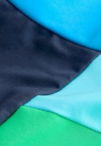 Kangasan tekstur yang menampilkan empat warna: navy, biru muda, teal, dan hijau. Materi tampak halus dan sedikit mengkilap dengan jahitan yang terlihat.