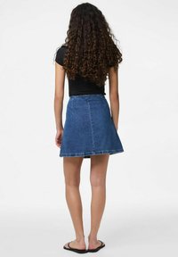 Denimhameen A-linjainen muotoilu, puolivälin reiden pituus, vaaleansininen väri ja risat helmassa, yhdistetty mustaan, tiukkaan puseroon ja sandaaleihin.