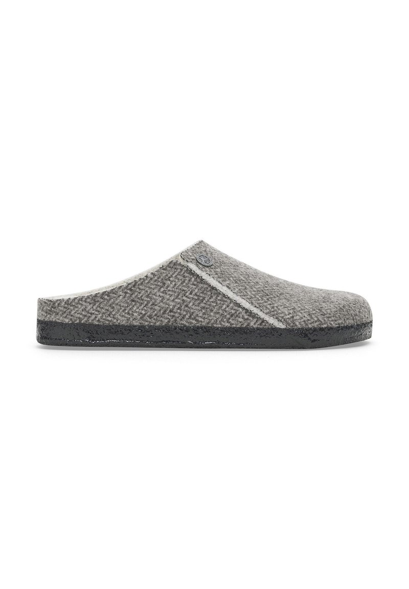 Chausson en laine gris avec un motif en chevrons, texture douce et semelle en caoutchouc noir contrastante. Présente un accent de logo sur le côté.
