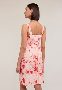 Ljusrosa klänning med ett röd-mönstrat tie-dye mönster, fyrkantig halsringning, tjocka axelband och figursydd midja, med ett mjukt tyg och knälång längd.