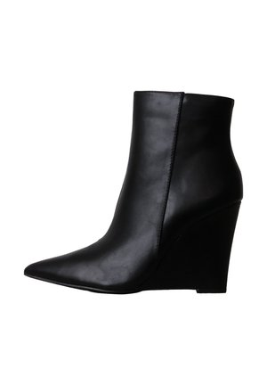 Bottine noire en cuir à bout pointu avec un talon compensé haut et une surface supérieure lisse vue de profil.