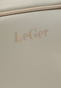 Υφασμάτινη επιφάνεια σε μπεζ απόχρωση με ανάγλυφο το όνομα της μάρκας "LeGer" σε τόνους που ταιριάζουν με το μπεζ.