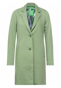 Cappotto verde in misto cotone con design sartoriale, chiusura con un bottone e due tasche frontali. Presenta una fodera interna a fantasia.