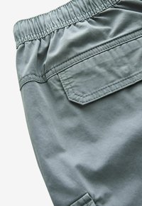 Grå bomuldsshorts med elastisk talje, som har en baglomme og en glat overflade. Stof er blødt og holdbart.