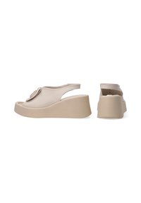 Beige wedge sandalen van soepel leer, met een ronde decoratieve accent aan de voorkant en een slingback ontwerp voor gemakkelijk aan- en uittrekken.