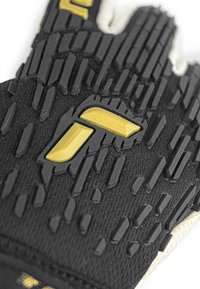 Schwarzer Handschuh mit strukturiertem Griff und erhabenen Gummielementen. Gelbe Akzente in der Nähe des Handgelenks. Robuster Stoff mit enger Passform.