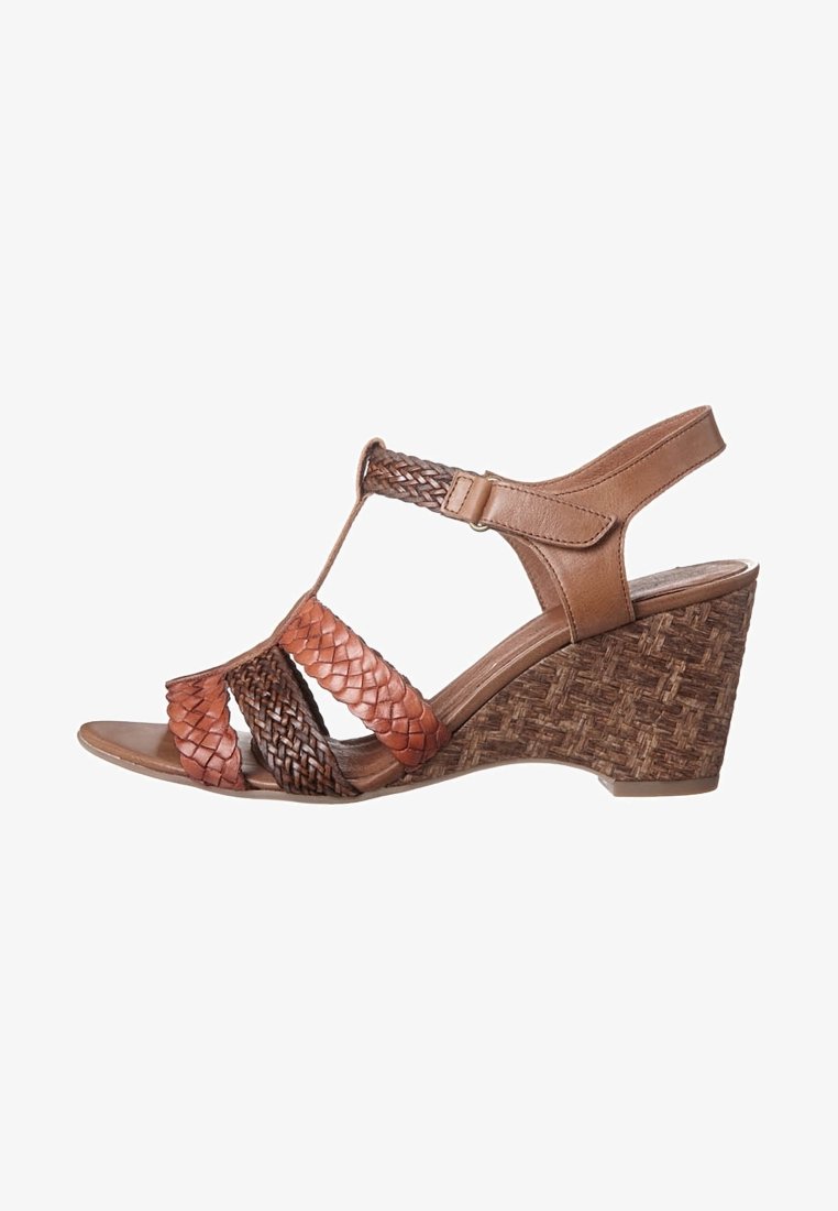 Sandalias de cuña marrones con correas de cuero trenzado y un tacón de corcho trenzado texturizado. Cierre de hebilla en la correa del tobillo. Diseño de punta abierta.