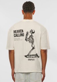 Oversized T-Shirt aus Baumwolle in Off-White mit einem schwarzen Skelettgrafik und Text, kurzen Ärmeln und geradem Saum.