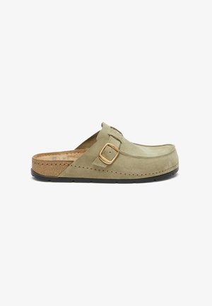 Green suede slip-on shoe with a cork midsole, featuring a brass buckle accent and a textured black rubber sole.