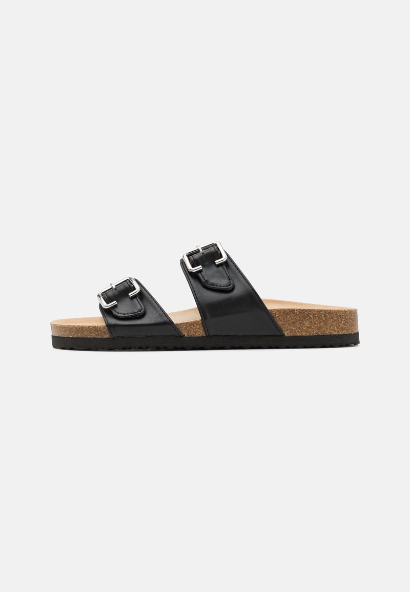 Black leather slide sandals with two adjustable silver buckles, cork footbed, and textured rubber outsole for grip. Flat design.