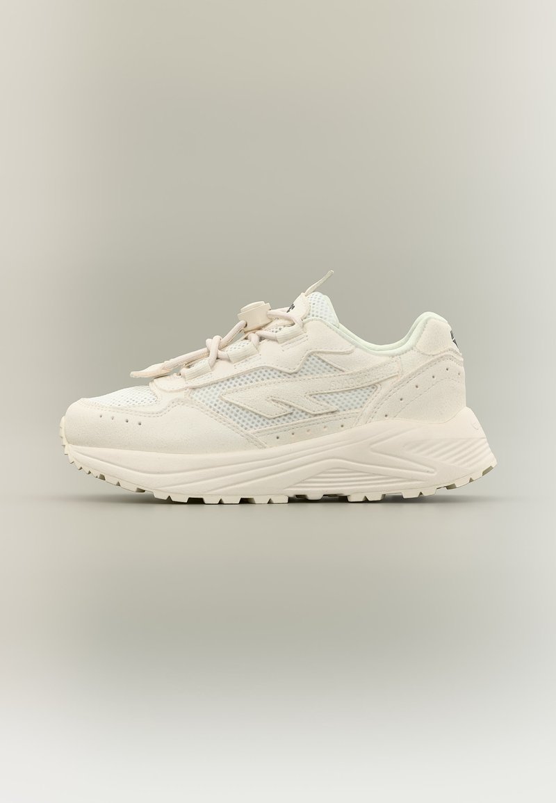 Fehér sportcipő hálós és velúr felsőrésszel, vastag talppal, cipőfűzőzéssel és állítható kapoccsal, egyszínű semleges háttér előtt.