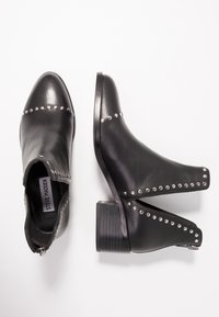 Black leather ankle boots with silver studs along the sides, a chunky heel, and a zip closure. Smooth texture with a pointed toe design.