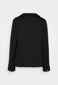 Chemise noire à manches longues avec col, présentant une texture lisse, des fentes sur les côtés et des accents en boutons au niveau des poignets. Design simple et élégant.