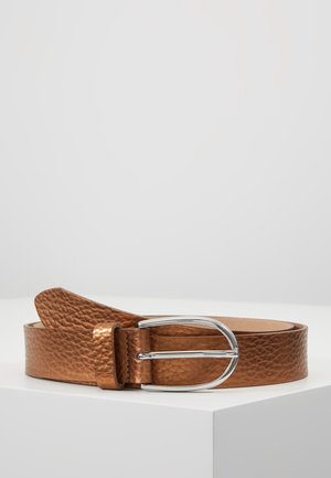 Ceinture en cuir marron texturé avec boucle en métal argenté arrondie posée sur une surface blanche inclinée.
