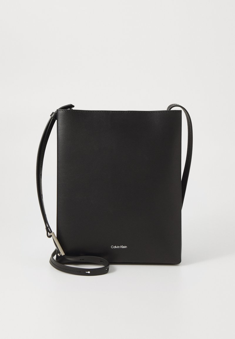 Black leather crossbody bag with a minimalist design, featuring a rectangular shape, adjustable strap, and silver branding accent.