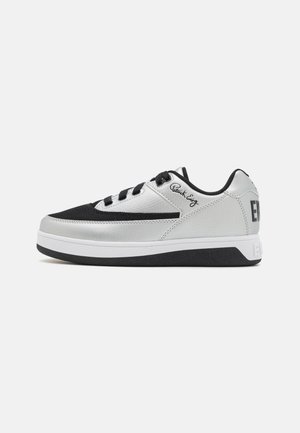 Baskets de sport noires et argentées avec une tige texturée, semelle intermédiaire blanche, semelle extérieure noire et lacets. Présente un détail de logo sur le côté.