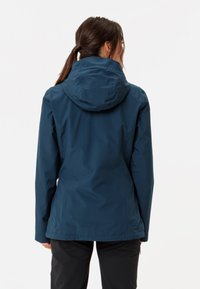 Giacca impermeabile blu navy con cappuccio aderente, tasche con zip, polsini regolabili e una texture liscia e opaca. Progettata per l'uso all'aperto.