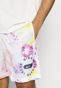 Sportliche Mesh-Shorts in Weiß mit bunten Blumenmustern in Pink, Lila und Gelb; versehen mit einem schwarzen Nike-Logo und Standardausgabe-Text.