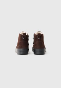 Brune sued ankle boots med en sort gummisåle, med lynlås og minimalistiske metaldetaljer. Glat tekstur med blødt for.