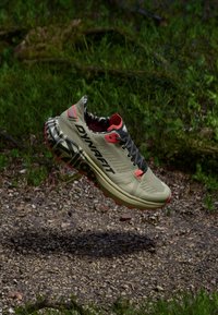 Ελαφριά αθλητικά παπούτσια για τρέξιμο σε μονοπάτια σε χακί με κόκκινες λεπτομέρειες. Διαθέτουν αναπνεύσιμο επάνω μέρος από δίχτυ, μαξιλαρωμένη σόλα και μοτίβο στην εξωτερική σόλα για καλύτερη πρόσφυση.