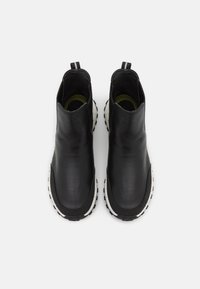 Stivaletti alla caviglia in pelle nera con finitura strutturata e suole in gomma bianche. Dotati di linguette per facilitare la calzata e interno imbottito.