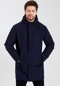 Parka bleu marine avec capuche, poches zippées et coupe droite. Fabriquée en matériau lisse et isolé pour plus de chaleur.