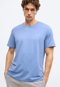 T-shirt de manga curta azul claro, feita de tecido macio e liso, com decote redondo e um pequeno logótipo "BOSS" bordado no peito.