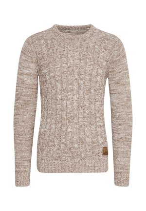 Neulepusero vaaleanruskeana, jossa on ristikkäisiä tekstuurikuvioita. Pitkät hihat, pyöreä kaula-aukko ja pieni nahkainen logopatch alhaalla.