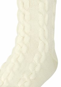 Ecrufarbene gestrickte Socke mit strukturiertem Zopfmuster, die einen gerippten Schaft und glattes, weiches Material aufweist.
