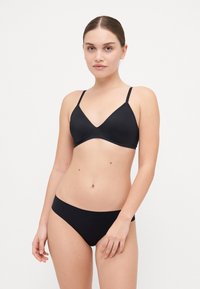Ensemble de bikini noir comprenant un haut bralette à décolleté en V avec des bretelles réglables et un bas taille basse assorti. Tissu lisse avec des coutures minimales.