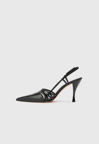 Svart läder högklackad slingback-sko med spetsig tå, korsande remdesign och smal stilettklack. Slät textur och minimala accenter.