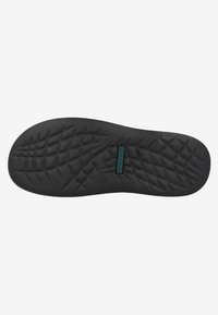 Black rubber shoe sole with textured grip pattern, featuring a central logo patch. Designed for traction and durability.