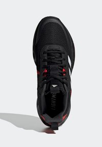 Zapatilla deportiva negra con una parte superior de malla texturizada, puntera reforzada, acentos rojos y detalle de logo blanco. Diseño con cordones y cuello acolchado.