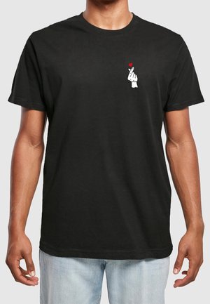 Camiseta de algodón negra con un pequeño gráfico blanco de una mano con un corazón en el área del pecho izquierdo. Mangas cortas, corte relajado.